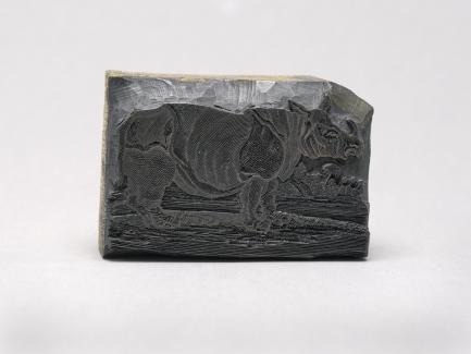 A wood printing block with a rhinoceros carved into it.