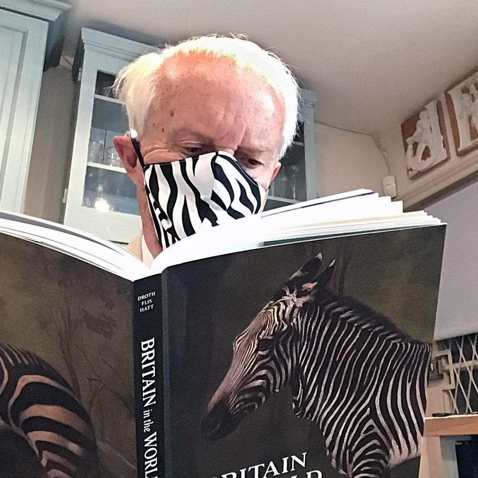 John Baskett reading "Britain in the World" wearing a Neville Wisdom face mask, photo courtesy of John Baskett