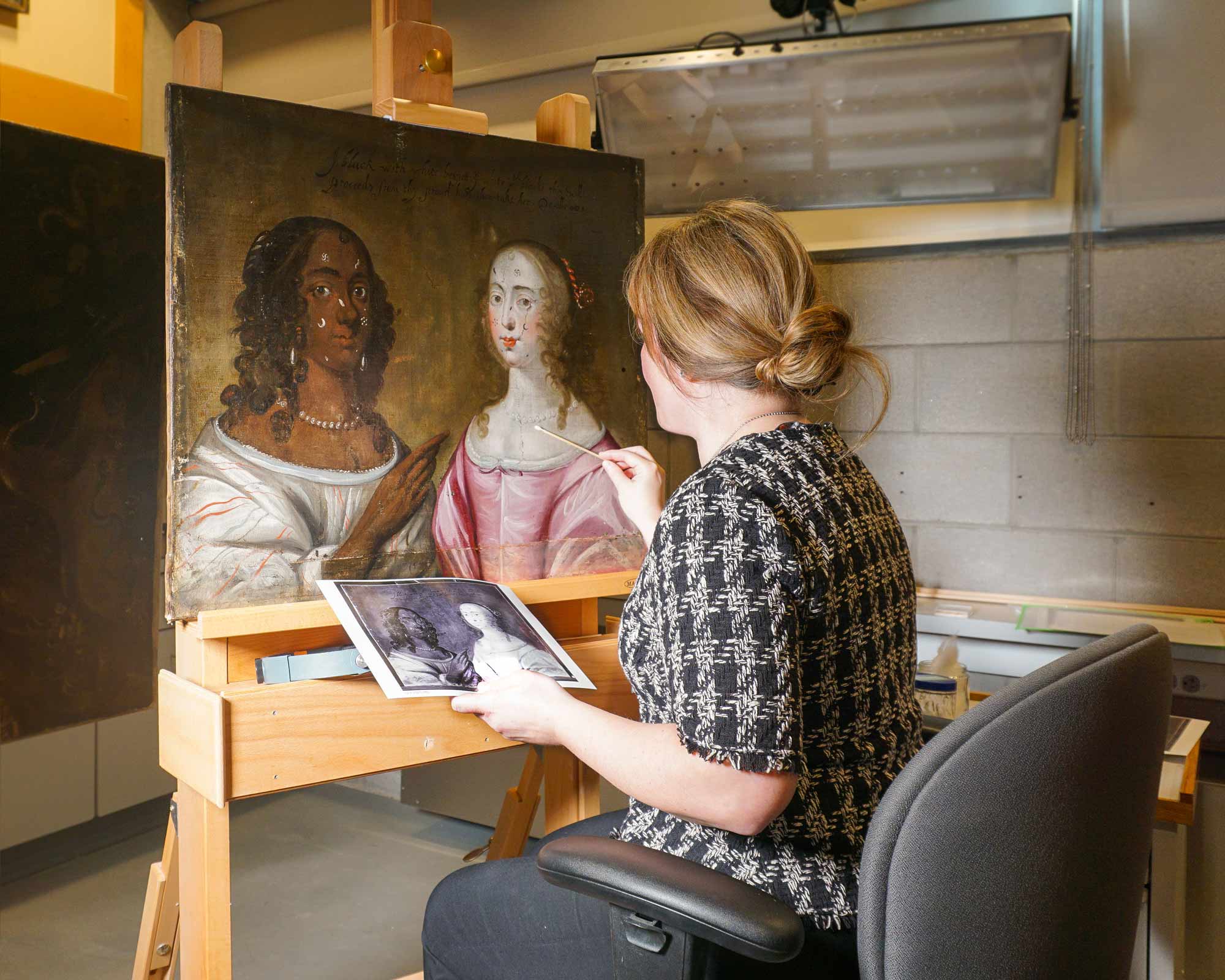 woman with blond hair treating a painting 