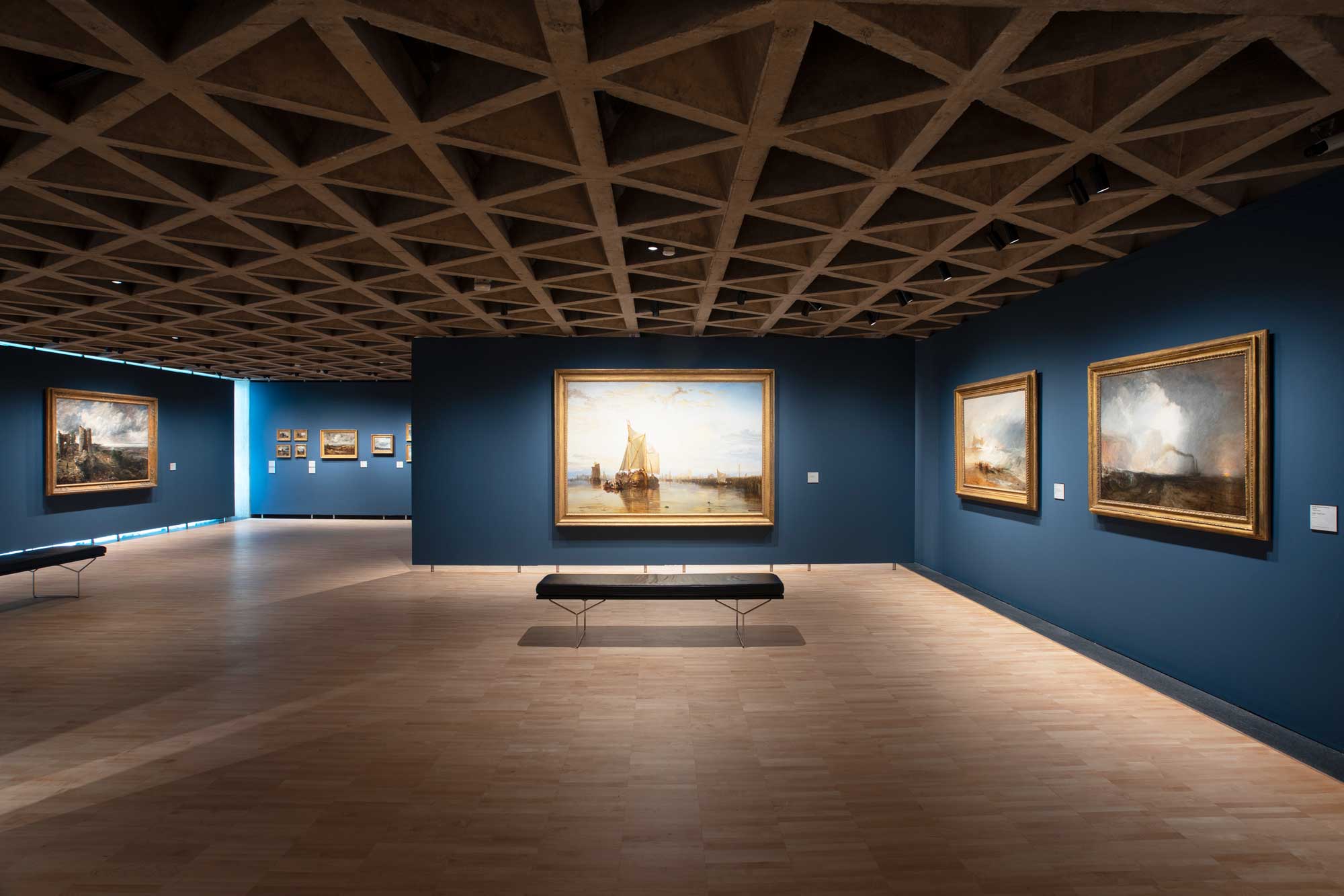 installation view of paintings inside a room painted a deep blue
