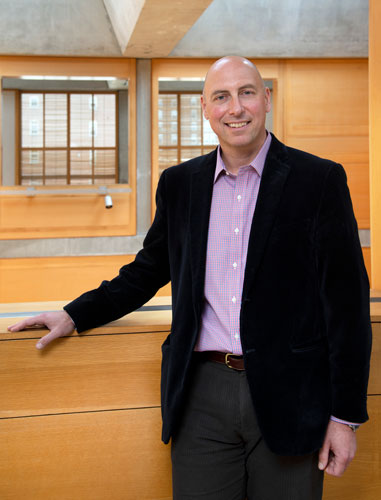 man wearing a dark blazer smiling at the camera