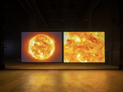 installation view of two screens with an image of the sun and a close up of the sun
