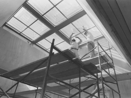 two people on a scaffold under skylights