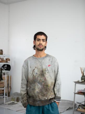 man wearing clothes with paint on them looking at the camera